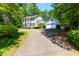 Charming two-story home with a well-manicured lawn, mature trees, and a brick driveway leading to an attached garage at 3605 Sewell Mill Rd, Marietta, GA 30062