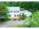 Traditional two-story home with a lush front lawn, mature trees, and a brick driveway leading to an attached garage at 3605 Sewell Mill Rd, Marietta, GA 30062
