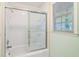 Cozy bathroom featuring a shower over bath, a window, and white tile at 170 Mark Nw Trl, Sandy Springs, GA 30328