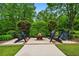 A cozy outdoor fire pit area with Adirondack chairs is surrounded by lush landscaping and mature trees at 1415 N Flat Rock Rd, Douglasville, GA 30134