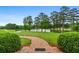 Scenic view of a brick path leading towards a serene lake, framed by manicured bushes and mature trees at 1415 N Flat Rock Rd, Douglasville, GA 30134