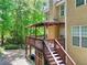 Exterior of tan home featuring a covered deck, staircase, and green backyard with trees at 1615 Mount Mckinley Dr, Grayson, GA 30017