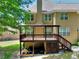 Exterior of tan home featuring a covered deck, staircase, and green backyard with trees at 1615 Mount Mckinley Dr, Grayson, GA 30017