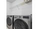 Laundry room with modern stainless washer and dryer and wire rack for storage at 5885 Raventree Ct, South Fulton, GA 30349