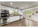 Well-lit kitchen featuring stainless steel appliances, white cabinetry, and access to outdoor space at 725 Danbridge Way, Roswell, GA 30076