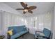Enclosed sunroom featuring large windows, white curtains, blue sofa and a ceiling fan at 324 Madeline Way, Temple, GA 30179