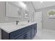 Bathroom featuring double sinks, marble counters, blue cabinets with black hardware and octagonal window at 7074 Ravenwood Ln, Lithonia, GA 30038