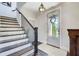 Bright foyer showcasing hardwood floors, staircase with dark wood banister, and stylish light fixture at 164 Inwood Walk, Woodstock, GA 30188