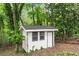 Backyard white utility shed with a black door and windows surrounded by mature trees at 800 Breckinridge Sw Rd, Marietta, GA 30064