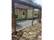 Backyard patio area with a dark pergola and a mix of stone and concrete surfaces at 1150 Hillary Ln, Lawrenceville, GA 30043