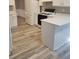 Eat-in kitchen featuring white cabinets, quartz countertops, black appliances, and modern wood-look laminate flooring at 1150 Hillary Ln, Lawrenceville, GA 30043