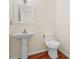 A bathroom with a modern pedestal sink and toilet, accentuated by warm wood floors at 557 Lawton Sw St, Atlanta, GA 30310