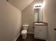 A half bathroom features a single sink vanity, toilet, modern light fixture, and dark laminate flooring at 241 Coral Cir, Mcdonough, GA 30253