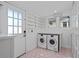 Bright laundry room with modern washer and dryer, built-in shelving, and charming pink-tiled floors at 28 Peachtree Hills Ne Ave, Atlanta, GA 30305