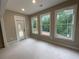 Bright living room featuring three large windows looking to the green backyard and outdoor access at 6861 Ga Hwy 5, Douglasville, GA 30135