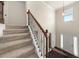 Carpeted staircase with wood and iron railing leading to the front door with decorative lighting and trim at 3257 Alhambra Cir, Hampton, GA 30228