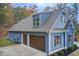 Spacious three-car garage with carriage-style doors, complemented by lush landscaping and manicured lawn at 401 Night Hawk Ct, Canton, GA 30114