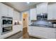 Bright kitchen boasts white cabinets, stainless steel appliances, and a grey tile backsplash at 401 Night Hawk Ct, Canton, GA 30114