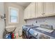 Well-organized laundry room with blue washer/dryer, white cabinets, and a window at 401 Night Hawk Ct, Canton, GA 30114