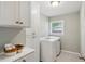 Well-lit laundry room featuring white cabinetry, a window, and a modern washer and dryer at 1155 Moores Mill Nw Rd, Atlanta, GA 30327