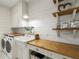 Modern laundry room with white cabinets, wood countertops, and stainless steel appliances at 230 Pebble Trl, Alpharetta, GA 30009