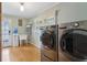 Bright laundry room featuring stainless steel washer and dryer, wash sink, hardwood floors, and a window at 5155 Pine Branch Pt, Atlanta, GA 30338