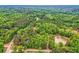 Lush, expansive aerial view of property surrounded by dense, mature forest, with a pond and winding roads at 5419 Tyree Rd, Winston, GA 30187