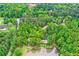 Aerial view of a home and pond nestled in a green, wooded landscape with a private lake at 5419 Tyree Rd, Winston, GA 30187