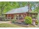 Exterior angle view featuring a covered porch, stone chimney and nicely landscaped flower beds at 5419 Tyree Rd, Winston, GA 30187