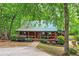 Charming cottage-style home with a metal roof and inviting covered front porch surrounded by trees at 5419 Tyree Rd, Winston, GA 30187
