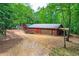 Exterior view of the property featuring a red garage and storage area surrounded by mature trees at 5419 Tyree Rd, Winston, GA 30187