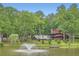 Beautiful exterior view featuring a tranquil pond with a fountain, a dock, lush greenery, and a charming home at 5419 Tyree Rd, Winston, GA 30187