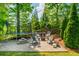 Inviting backyard patio with a trampoline, fire pit, and stone pavers surrounded by lush greenery at 7048 Bennington Ln, Cumming, GA 30041