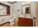 Bathroom featuring a wooden vanity, accent mirror, window alcove, and neutral color scheme at 7048 Bennington Ln, Cumming, GA 30041