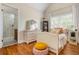 Bright bedroom with a white bed frame, hardwood floors, window with plantation shutters, and attached bathroom at 7048 Bennington Ln, Cumming, GA 30041
