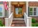 Inviting front door with glass panels, framed by brick, white railings, and an American flag at 7048 Bennington Ln, Cumming, GA 30041
