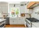 Bright kitchen featuring white cabinets, a farmhouse sink, stainless steel appliances, and hardwood floors at 7048 Bennington Ln, Cumming, GA 30041