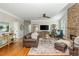 Spacious living room with a stone fireplace, hardwood flooring, ceiling fan, and stylish furnishings at 7048 Bennington Ln, Cumming, GA 30041