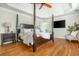 Bedroom with hardwood floors, tray ceilings, and a mounted television at 7048 Bennington Ln, Cumming, GA 30041