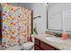 A charming bathroom features a granite countertop, cherry wood cabinets, and a colorful floral shower curtain at 2265 Venture Dr, Marietta, GA 30062