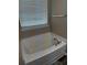 Close up of a white bathtub with tile surround and window blinds at 314 Meadows Ln, Canton, GA 30114