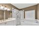 A bright bathroom featuring a glass shower, soaking tub, white vanity and a bronze fixtures at 1720 Ivey Trce, Cumming, GA 30041