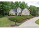 Charming tan home featuring lush landscaping, a curved driveway, and a welcoming front entrance at 1720 Ivey Trce, Cumming, GA 30041