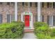 Charming brick home entrance with a bright red door, flanked by greenery and black shutters at 2034 Starfire Ne Dr, Atlanta, GA 30345