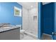 Bathroom with blue accent wall, marble countertop vanity, and a tiled walk-in shower at 4064 Post Rd, Winston, GA 30187