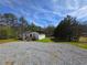 View of the house with a gravel driveway and a yard with mature trees at 4064 Post Rd, Winston, GA 30187