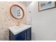 Stylish powder room featuring butterfly wallpaper, navy vanity with gold accents, and a round wood-framed mirror at 1435 Willis Lake Nw Dr, Kennesaw, GA 30152