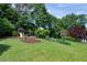 The expansive backyard offers mature landscaping, lush lawn, a playhouse, and flowering shrubs at 3331 Lockwood Sw Ct, Lilburn, GA 30047