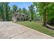 Front yard with a spacious driveway leading to a beautiful home surrounded by lush greenery and trees at 165 6Th St, Auburn, GA 30011