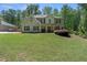 Charming two-story home with a well-manicured lawn and inviting front porch nestled amongst the trees at 165 6Th St, Auburn, GA 30011